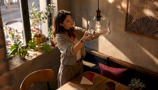 Woman adjusting decorative bulb in cozy living room