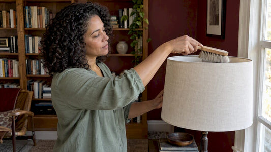 Woman gently dusting a linen lamp shade