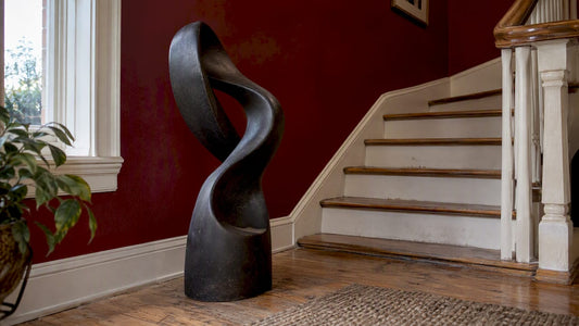Black abstract sculpture on a burgundy stair landing